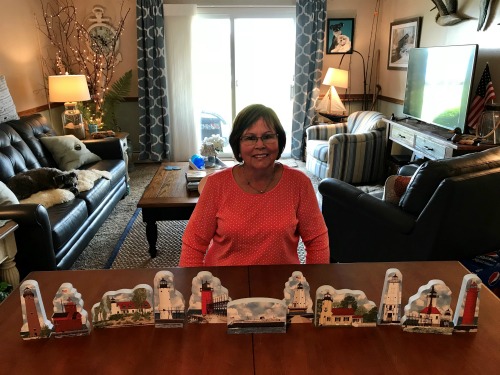 Sandy Lea with her newly unpacked Cat's Meow Michigan lighthouses in her Michigan vacation home.