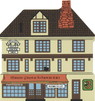 3/4" thick wooden replica of an illustrated building facade with a dark brown tiled roof, cream walls, blue window panes, an orange awning reading 'three french hens inn,' and a brick-red chimney.