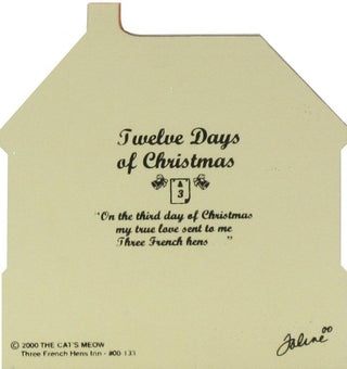 A house-shaped cream-colored wooden replica with black printed text reading 'Twelve Days of Christmas' and a quote from 'Three French hens' by Joline. Small copyright text at the bottom left reads '2000 THE CAT'S MEOW' and 'Three French Hens Ent.