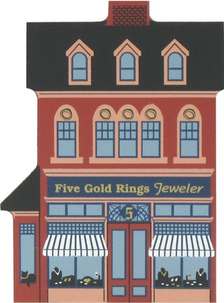 3/4" thick wooden replica of an illustration of a storefront building labeled 'Five Gold Rings Jeweler,' with a red facade, dark roof, blue windows, striped awnings, and a central door.