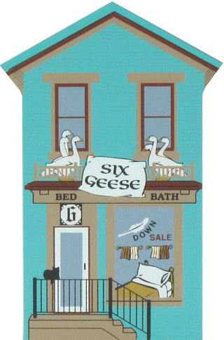 3/4" thick wooden replica of an illustration of a turquoise house facade with two windows, a front door, and a balcony. Two white geese sit on each upper balcony.