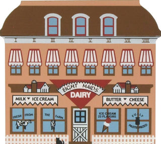 3/4" thick wooden replica of an Illustrated front facade of a dairy building with red-and-white awnings, blue windows, and signage reading 'Eight Maids Dairy' and 'Milk Ice Cream' and 'Butter Cheese'.