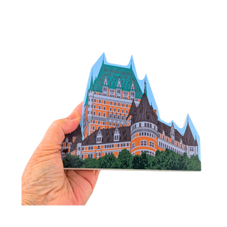 Hand holding a 3/4" thick wooden cutout of a castle illustration on a white background