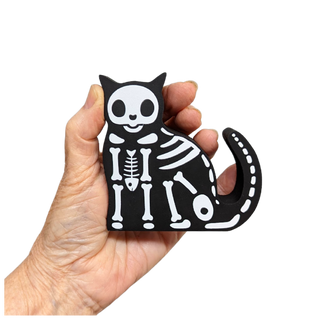 Hand holding a 3/4" thick wooden black cat skeleton toy against a white background