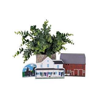 Scene of a fake plant and 3 3/4" thick wood models of a barn, two story house, and Amish family. 