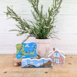 Decorative items including a plant, postcards, and a small house model on a wooden surface.