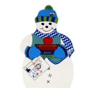 3/4" thick wooden replica with an Illustration of a snowman. The design includes a blue and green striped beanie, a blue and white checkered scarf, a red apple, and books labeled 'READING', 'GEOGRAPHY', 'MATH', and 'SCIENCE'.
