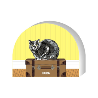 Wooden replica of a Cat on a suitcase with 'Dora' its name against a yellow background