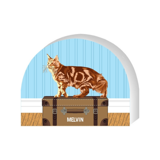 Wooden replica of a  Cat named Melvin standing on a suitcase with a blue door in the background