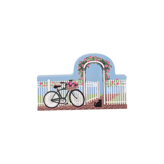 3/4" thick wooden illustration of a bicycle, flowers, and a cat in front of a white picket fence and floral archway.