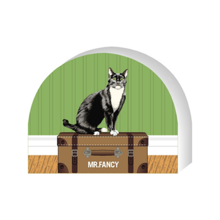Wooden replica of a Cat on a suitcase with 'MR. FANCY' branding against a green wall.