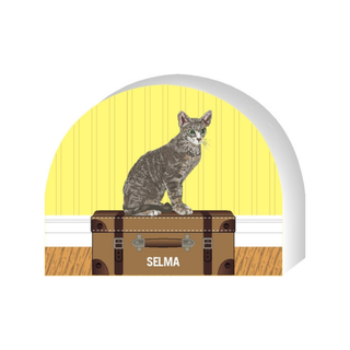 Wooden replica of a  Cat sitting on a suitcase with a yellow background and 'Selma' label