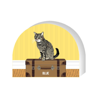 Wooden replica of a  Cat sitting on a suitcase with a yellow door in the background
