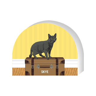 Wooden replica of a Illustration of a cat on a suitcase with 'Skye' labeled, set against a yellow background.