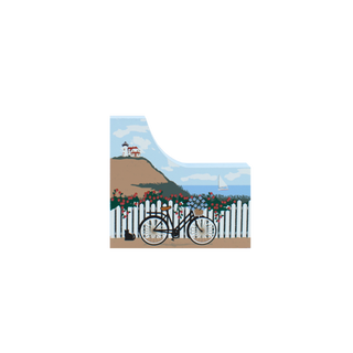 decorative wooden replica with a bicycle, flowers, sailboat in the ocean and lighthouse design with a blue sky