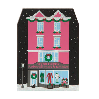 3/4" thick wooden replica with an illustration of a  house-shaped sign with a pink building, Christmas decorations, and clothing store display.