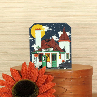 Halloween-themed shelf sitter with glow-in-the-dark details on a wooden surface with an orange flower.