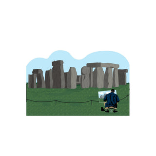 3/4" thick wooden cutout of a person painting Stonehenge with a blue sky and green grass.
