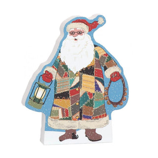 3/4" thick wooden replica with an Illustration of a Santa Claus in a multicolored patchwork coat, holding a lantern and wreath, on a white background.
