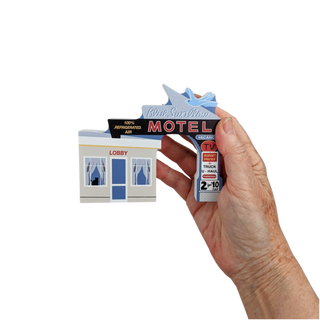 Hand holding a miniature model of a motel with 'Blue Swallow Motel' branding.