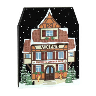 3/4" thick wooden replica with an illustration of a  festive building with 'Vixen's Stocking Stuffer Shop' on a snowy background.