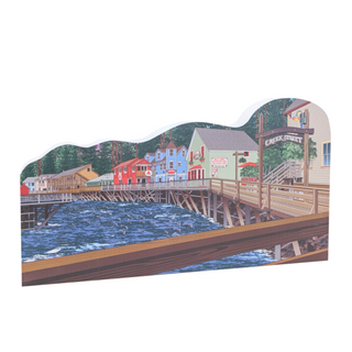 Wooden cutout of a town scene with buildings and a bridge over water with a sign that reads 'creek street'