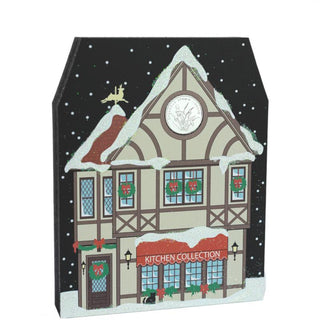 3/4" thick wooden replica with an illustration of a Christmas-themed building with a clock and snow on the roof, featuring 'Kitchen Collection' text.