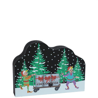 3/4" thick wooden replica with an illustration with cartoon characters pushing a cart labeled 'Cocoa' against a snowy background.