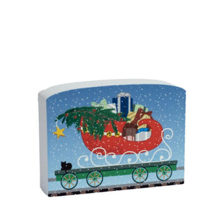 3/4" thick wooden replica with an illustration of a  Christmas scene featuring a sleigh, reindeer, and presents on a blue background.