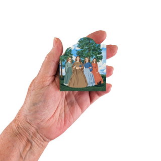 Hand holding a 3/4" wooden replica  with a vintage-style illustration of four women in dresses against a tree background.