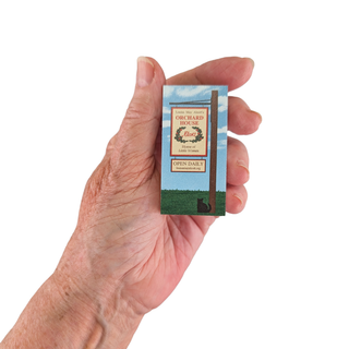 Hand holding a small wooden replica with a scenic design on a white background