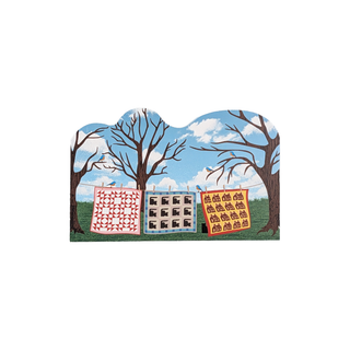 3/4" thick wooden illustration of quilts hanging between trees
