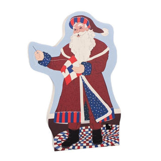 3/4" thick wooden replica with an Illustration of a Santa Claus knitting, featuring a red coat with white trim, a white beard, and patriotic red, white, and blue accents, set against a plain white background.