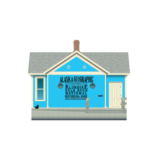wooden replica with an Illustration of a blue house with Alaska Geographic and Klondike Gold Rush National Historical Park text.