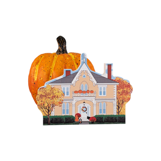 Pumpkin with a house cutout and autumn decorations on a white background