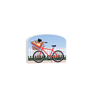3/4" thick wooden illustration of a red bicycle with a basket containing a cat and picnic items, against a blue sky and white picket fence background.