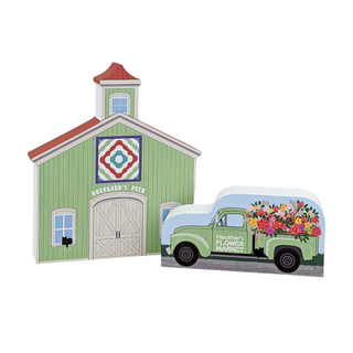 3/4" thick wooden illustrations of a green barn with a quilt design on the side and a vintage truck with flowers