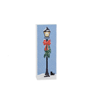 3/4" thick wooden replica with an illustration of a Christmas-themed design featuring a lamp post, red bow, and cat on a blue snowy background.