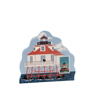 A die-cut decorative plaque featuring an illustrated lighthouse on a pier over blue water, with a postage stamp design on the right side, shown on a plain white background.