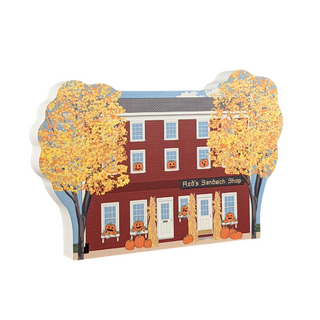 3/4" thick wooden Illustration of a red brick building with pumpkins and corn stalks on a white background