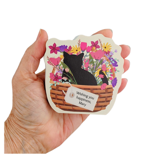 Hand holding a decorative 3/4" thick wooden cutout with a cat and floral design.