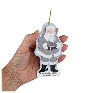 Hand holding a Christmas ornament with Santa Claus design and text on a white background