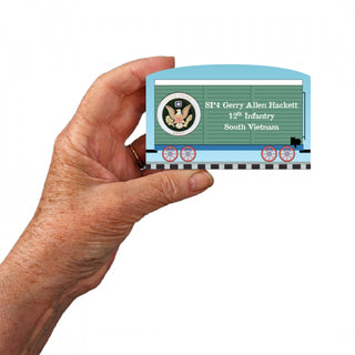 Hand holding a 3/4" Wooden replica with a train car with military-themed design on a white background