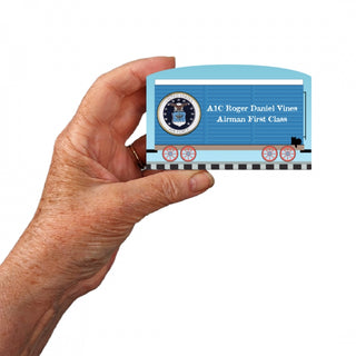 Hand holding a 3/4" Wooden replica with amilitary insignia and text on a white background