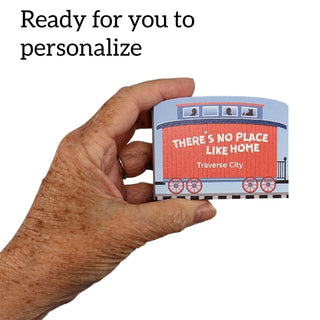 3/4" Wooden replica with a Hand holding a small container with 'There's no place like home Traverse City' text on a white background.