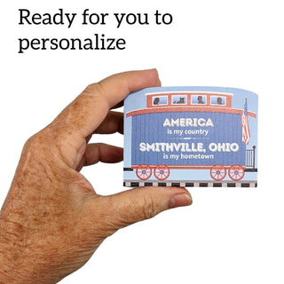 3/4" Wooden replica with a Hand holding a personalized product with text 'America is my country, Smithville, Ohio is my hometown' on a blue train design.