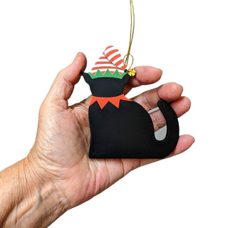 Hand holding a black cat-shaped ornament with a colorful hat on a white background