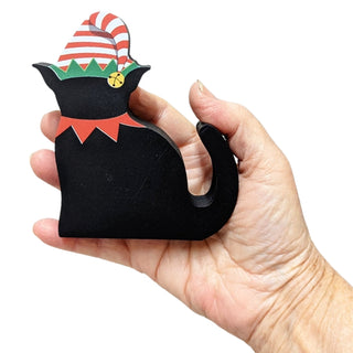 Hand holding a black cat-shaped ornament with a Santa hat on a white background