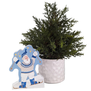 Decorative wooden cutout of a Santa Claus figure next to a potted plant on a white background