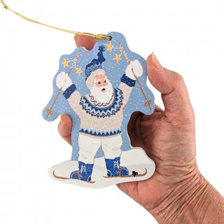 Hand holding a decorative ornament of a character in a blue and white outfit with skis on a white background